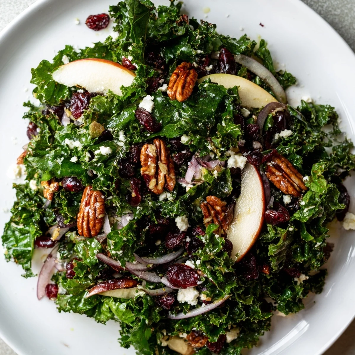 Close-up of a vibrant Winter Kale Salad with Pecans and Cranberries tossed in a zesty maple-Dijon vinaigrette, showcasing fresh ingredients.