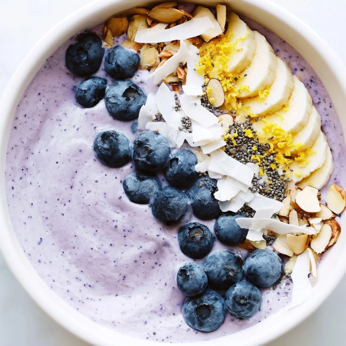 Vibrant purple Lemon Blueberry Smoothie Bowl garnished with coconut flakes and chia seeds, perfect for a healthy breakfast.