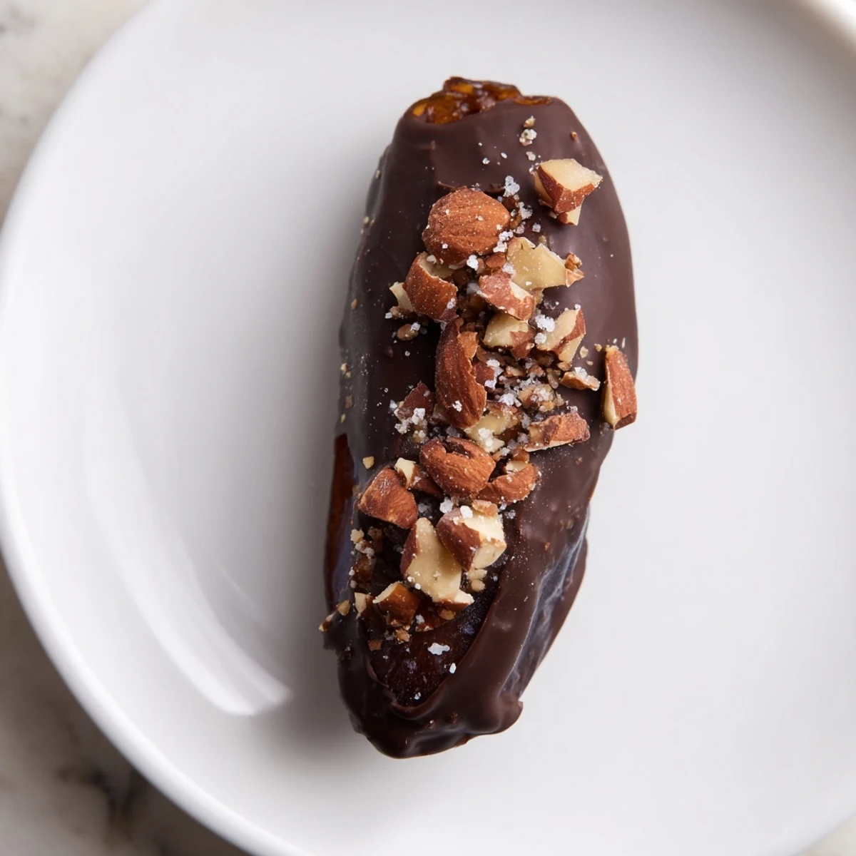 The finished Chocolate Covered Dates Stuffed with Almond Butter arranged on a white plate.