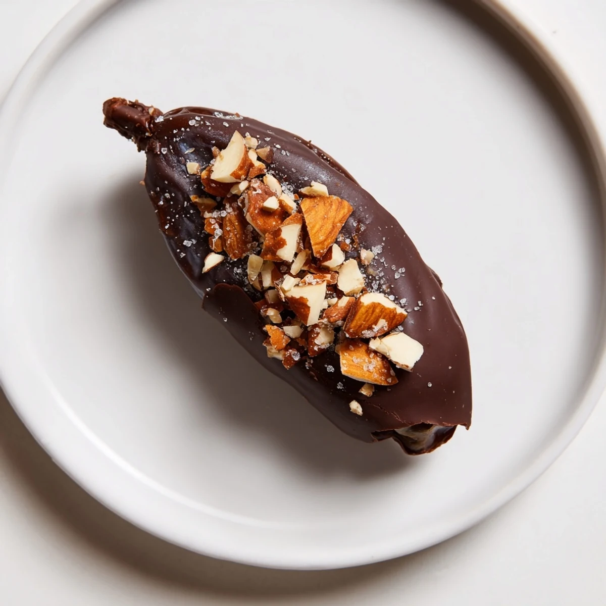 Melted dark chocolate coating sweet Medjool dates filled with creamy almond butter on a tray.