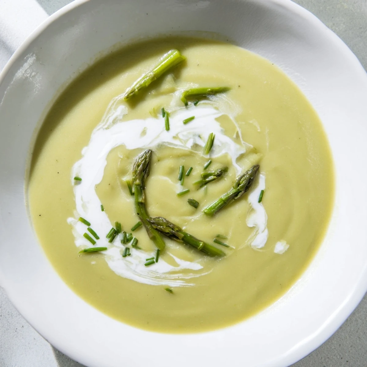 Velvety Creamy Asparagus Soup with Lemon served alongside crusty artisan bread and a glass of crisp Sauvignon Blanc on a rustic table.