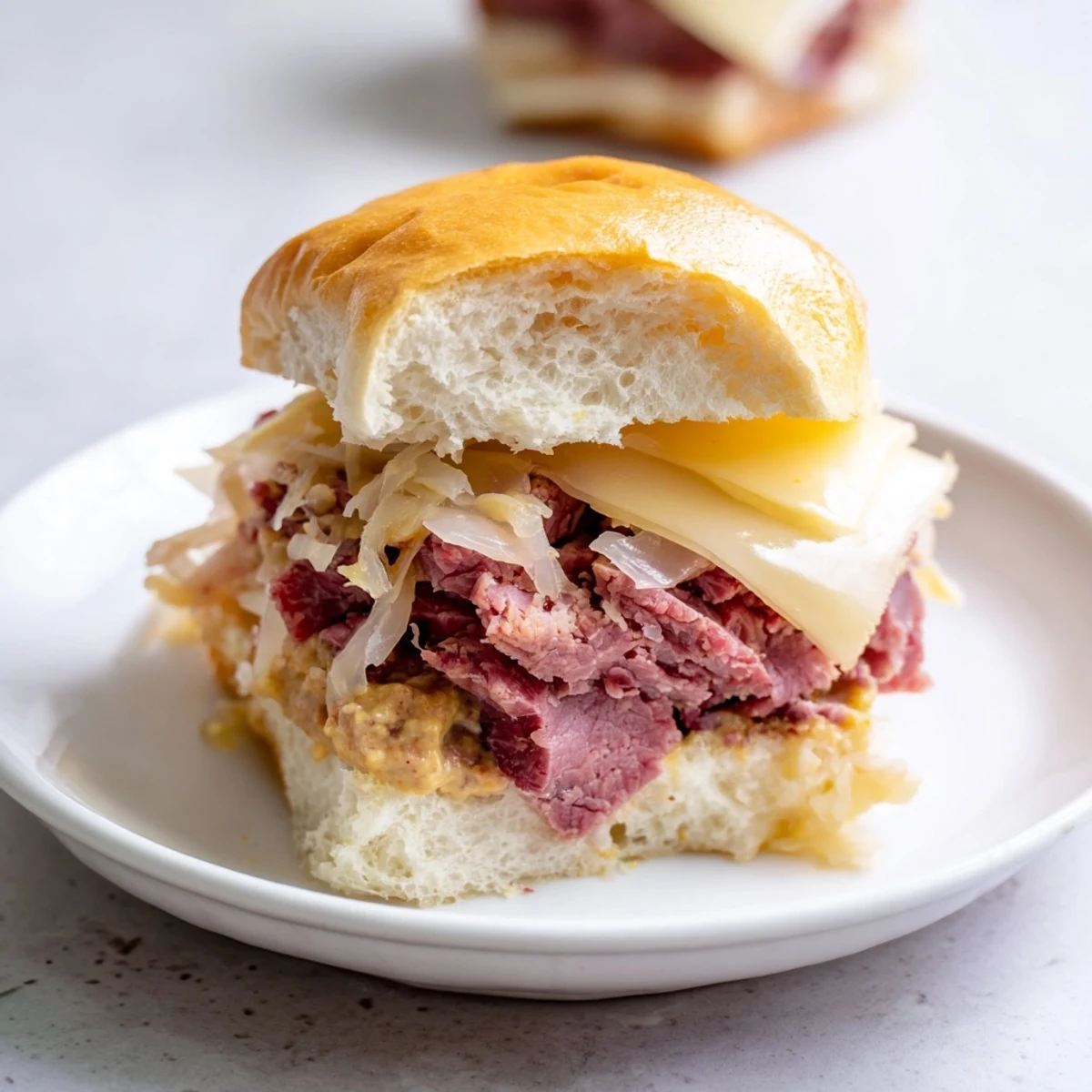 Freshly baked Corned Beef Sliders with Stone Ground Mustard ready for a party, garnished with chives and pickles.