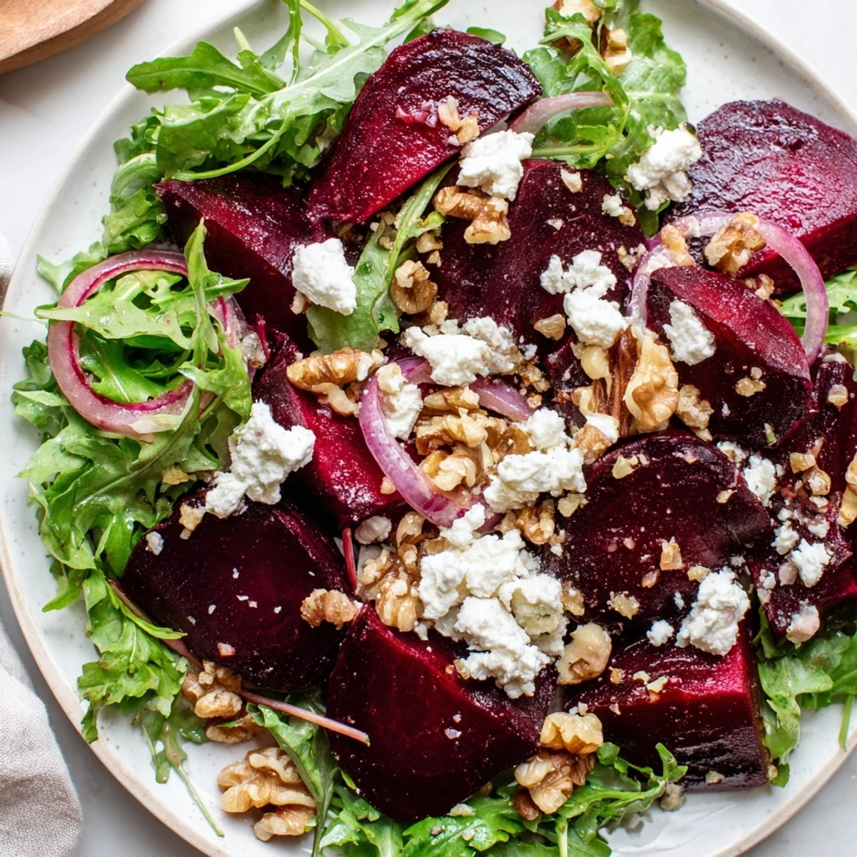 Roasted Beet Salad with Goat Cheese presented on a white platter with deep red beet wedges, creamy crumbles, and toasted walnuts
