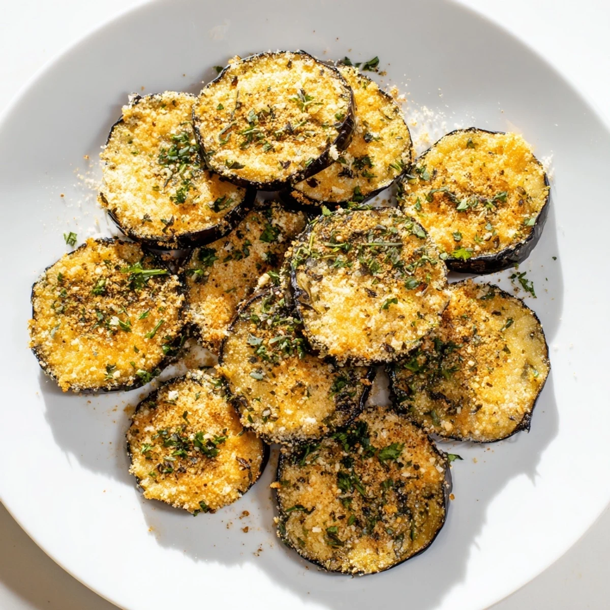 Golden roasted eggplant slices topped with crispy Parmesan and Mediterranean herbs for an easy appetizer.