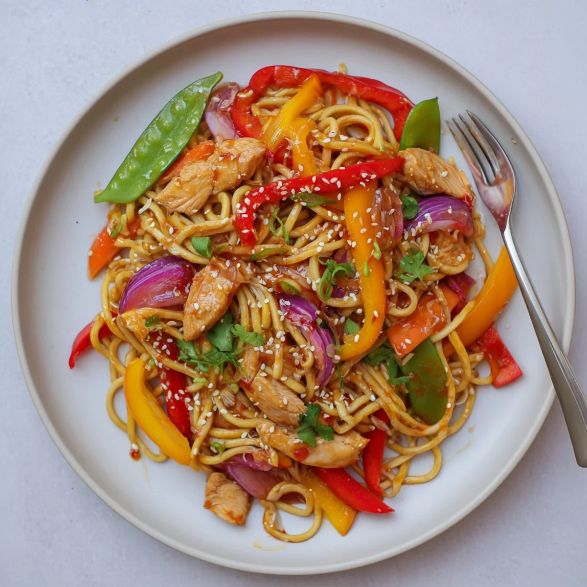 Close-up of Sweet Chilli Turkey Noodle Stir Fry showing glossy noodles and colorful vegetables with sesame seeds.