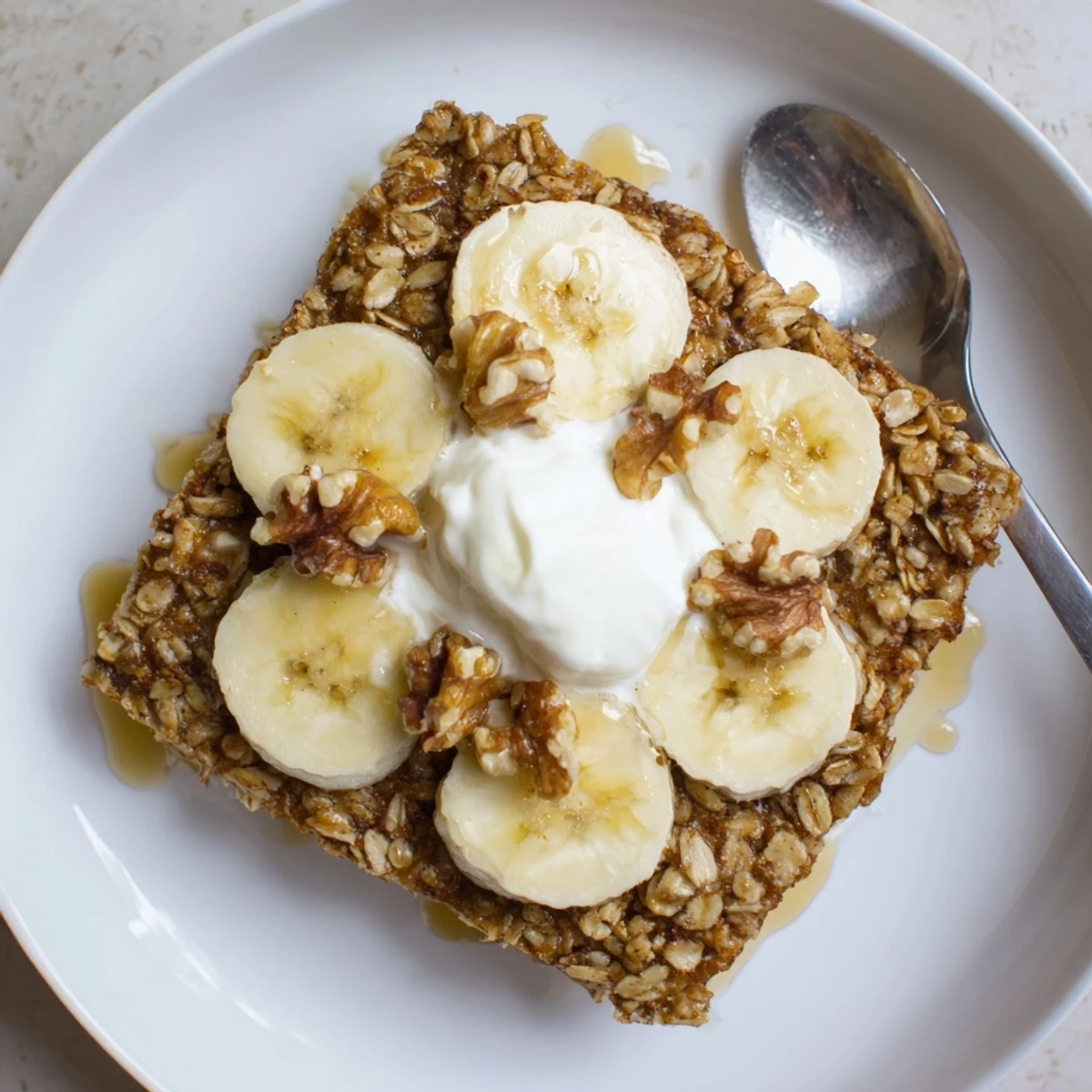 Warm Banana Baked Oatmeal with Greek Yogurt, a wholesome breakfast bake served in a baking dish with a side of fresh bananas.