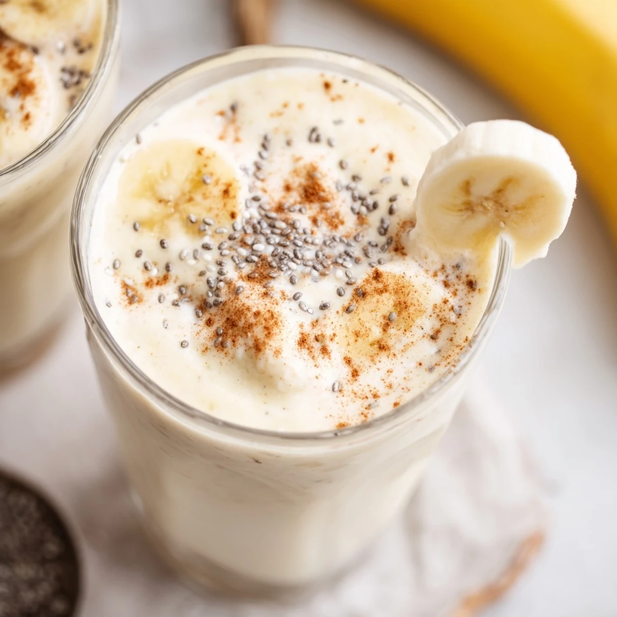 Creamy Greek yogurt banana smoothie poured into a glass topped with fresh banana slices