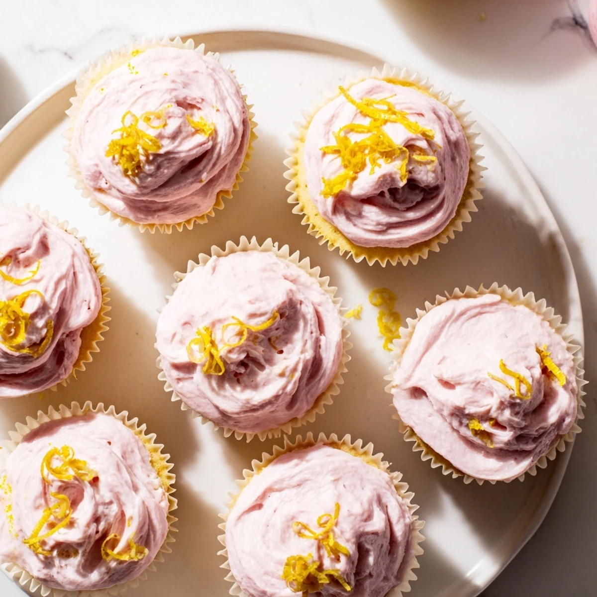 Zesty lemon cupcakes topped with naturally pink strawberry buttercream and fresh berry garnish