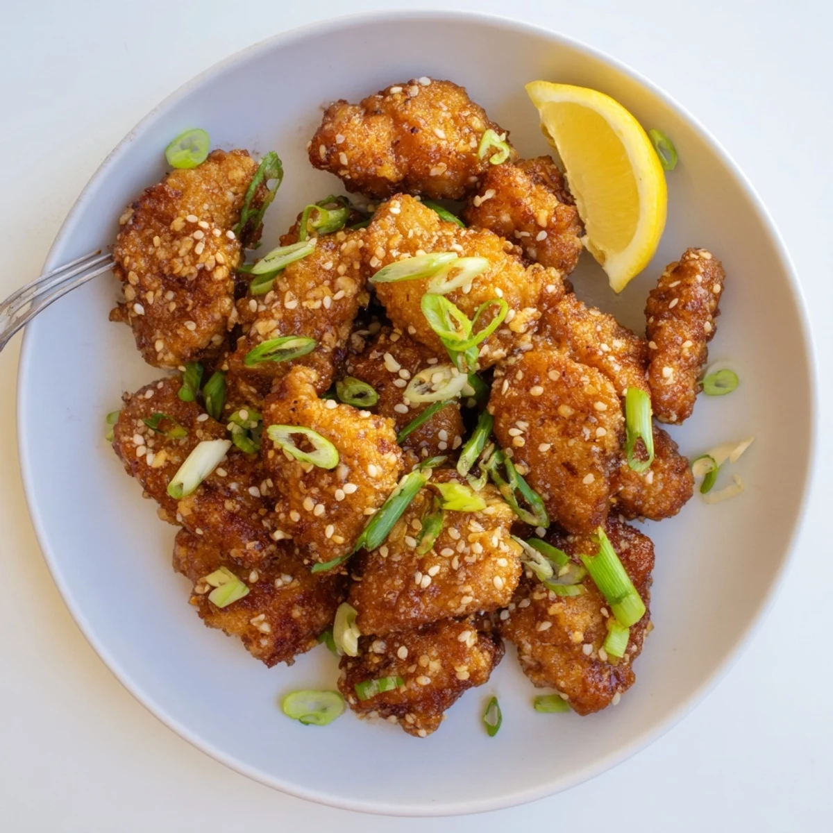 Golden brown Hawaiian Mochiko Chicken pieces arranged on a white serving platter with sesame seed garnish