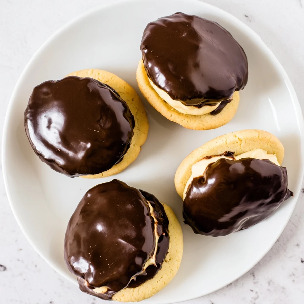 Bite-sized Boston Cream Pie Cookie Bites sandwiched with vanilla custard and topped with glossy chocolate glaze