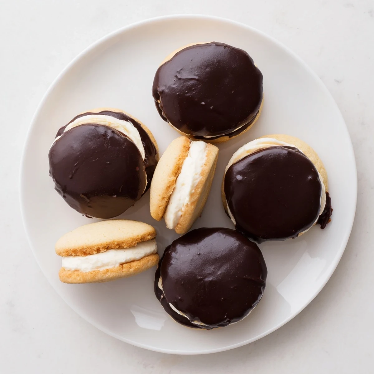 Soft vanilla cookie sandwiches filled with creamy custard and drizzled with rich semi-sweet chocolate topping