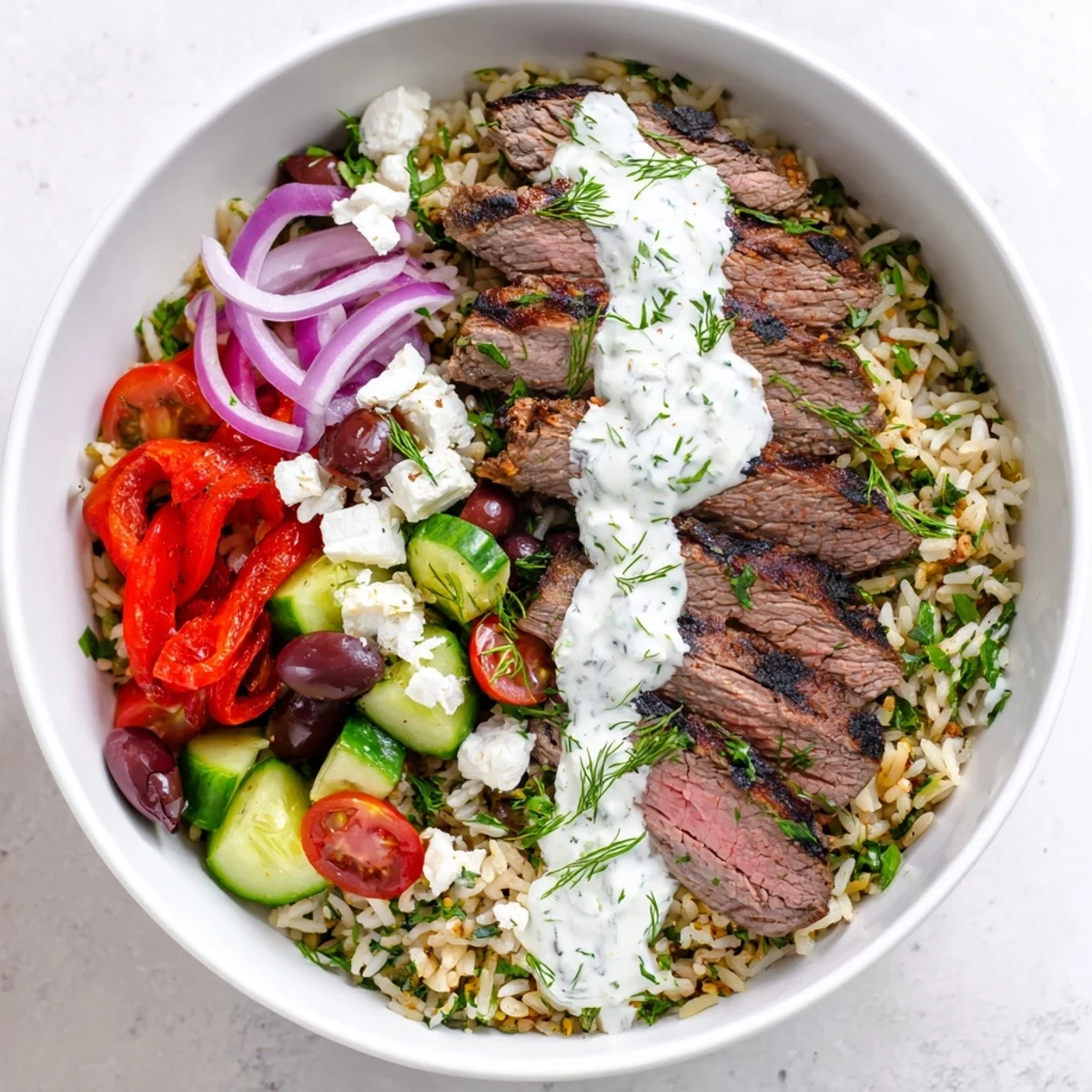 Protein-packed Mediterranean steak bowl topped with juicy grilled steak, cherry tomatoes, cucumber, and feta