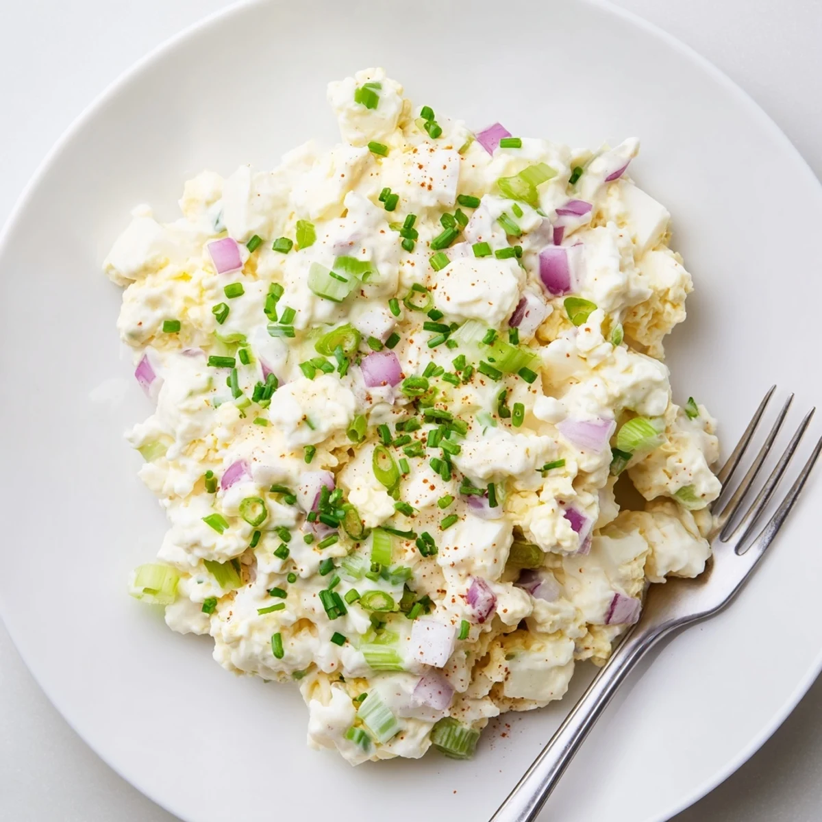 Creamy cottage cheese egg salad with chopped eggs and fresh herbs in a white bowl