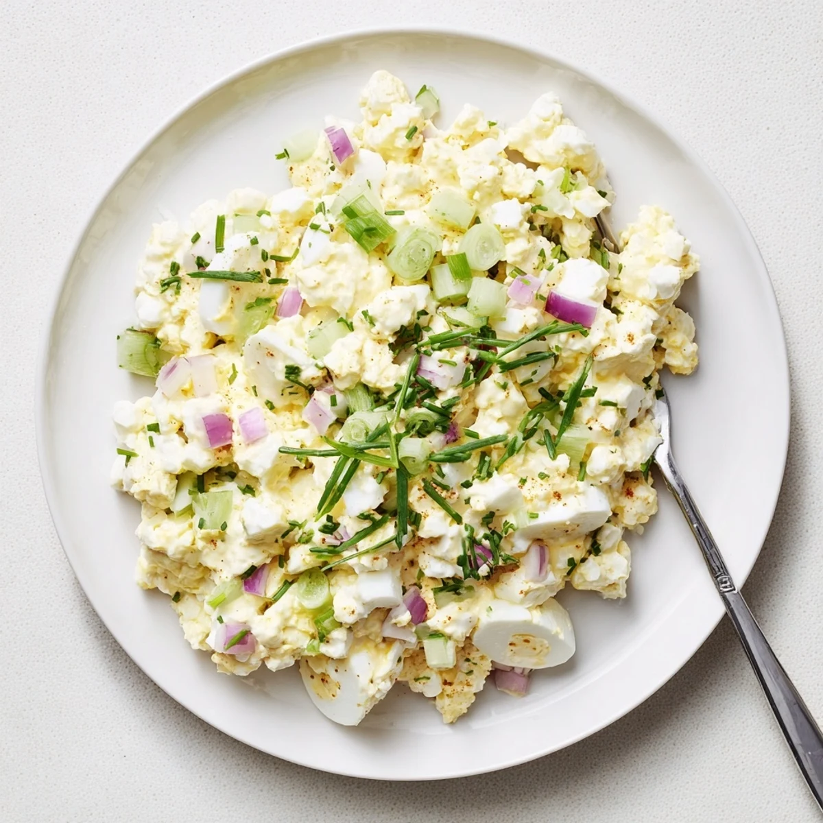 Spoonful of cottage cheese egg salad topped with chives and smoked paprika garnish