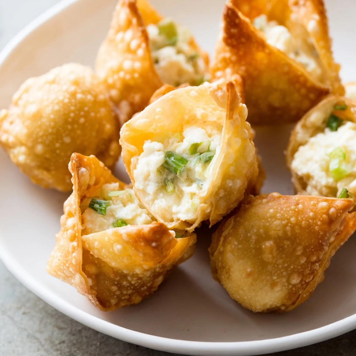 Golden fried Crab Rangoon Bombs arranged on white plate with sweet chili dipping sauce
