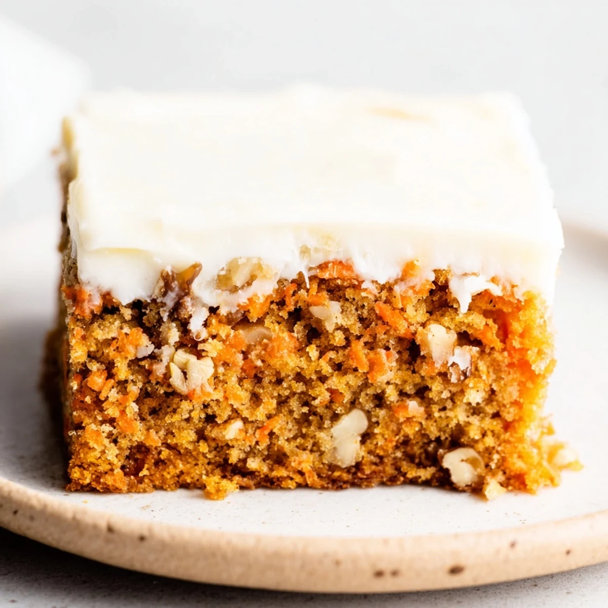 Decadent carrot cake bars featuring moist grated carrot cake beneath swirls of luscious cream cheese frosting