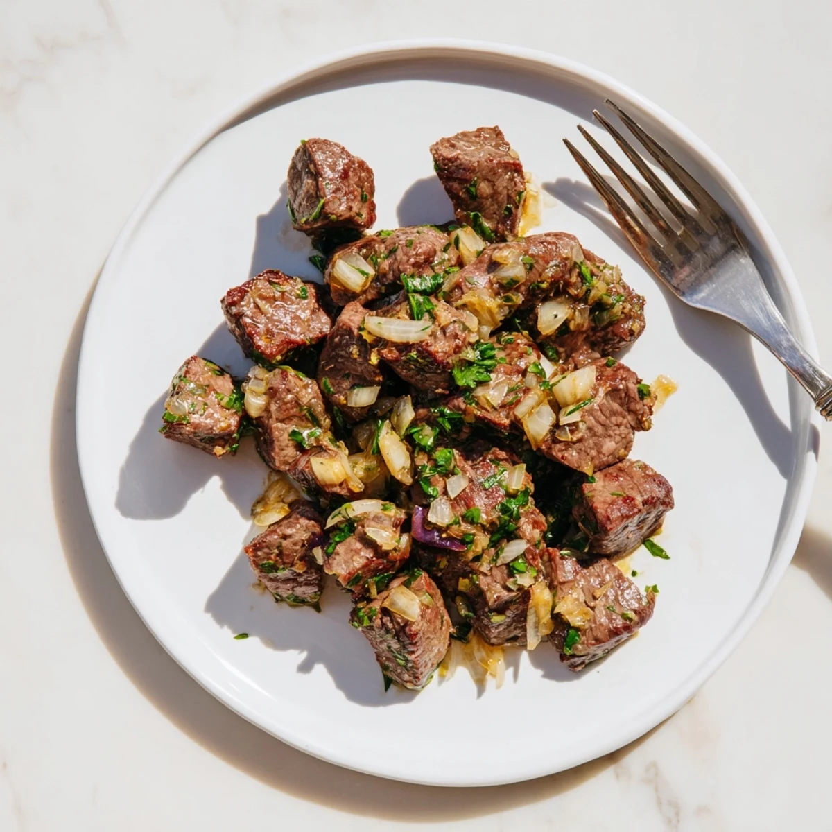 Tender crockpot steak bites coated in rich garlic butter sauce with fresh parsley garnish