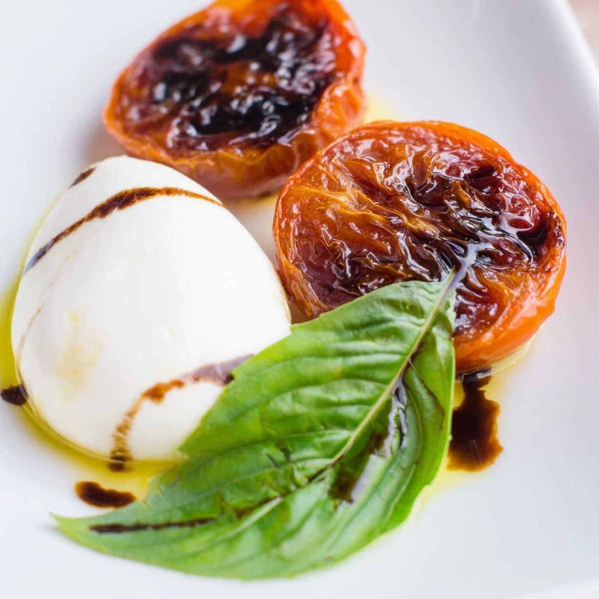 Colorful Caprese salad featuring roasted tomatoes layered with soft cheese and fresh herbs topped with tangy balsamic dressing