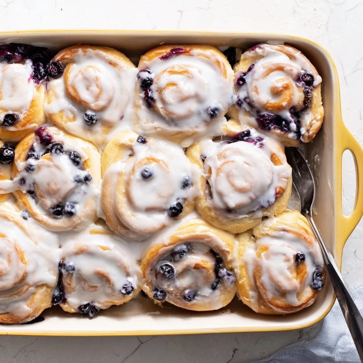 Soft baked lemon blueberry rolls sliced open revealing purple berry swirls and sweet filling