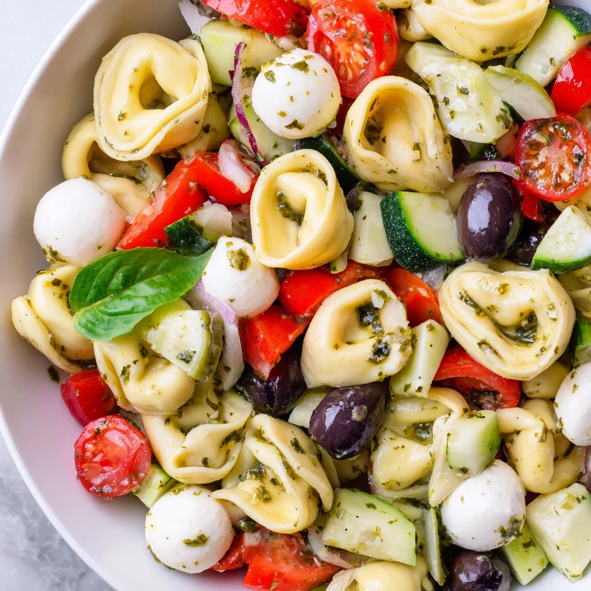 Cheese tortellini tossed with crisp vegetables and fresh basil in a vibrant picnic salad