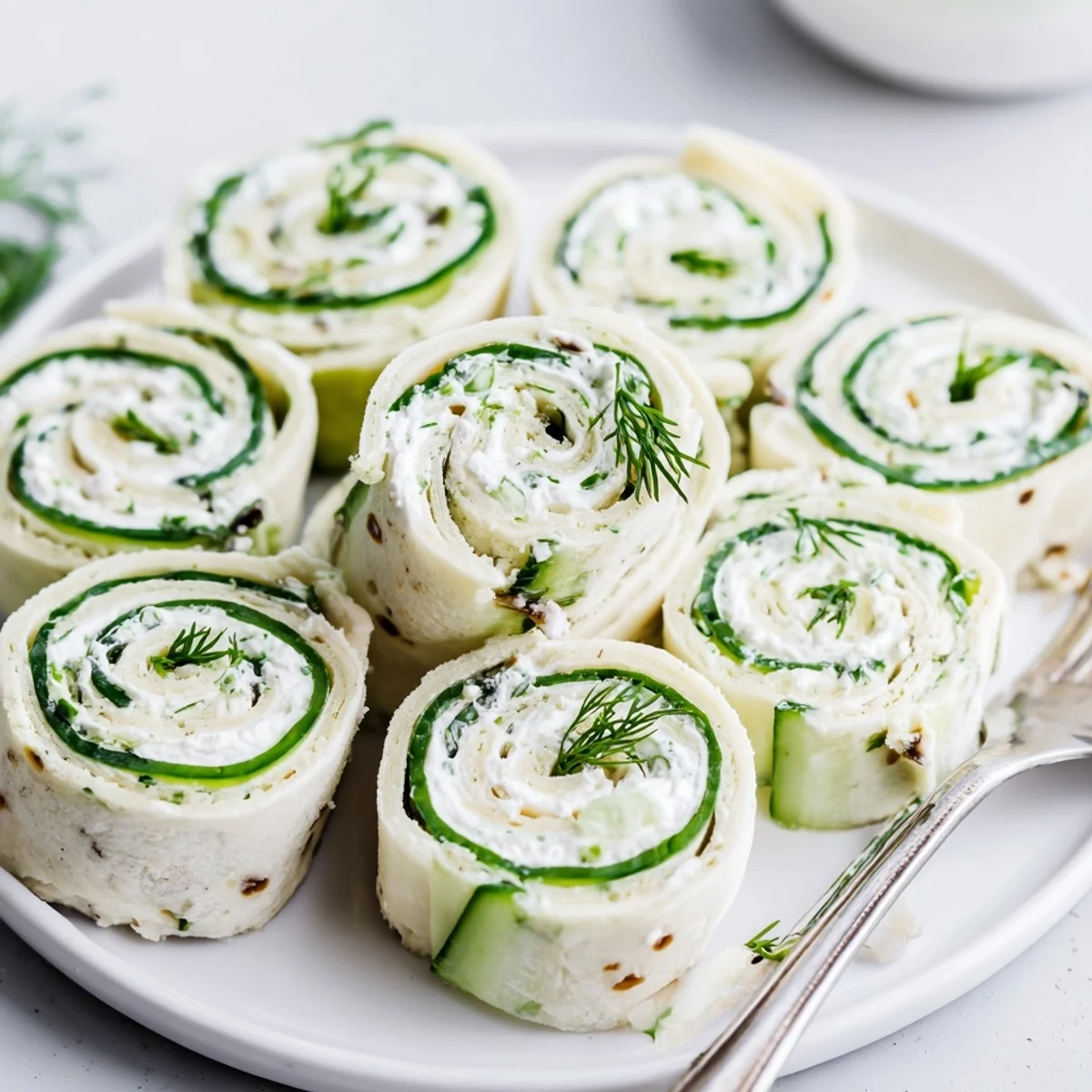 Cucumber And Dill Pinwheels chilled on a platter, creamy filling, crisp cucumber