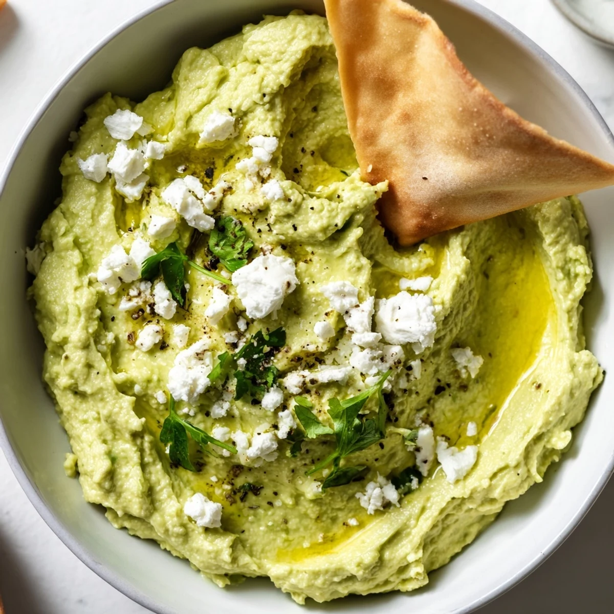Bright, zesty Creamy Avocado Feta Dip topped with olive oil, cilantro.