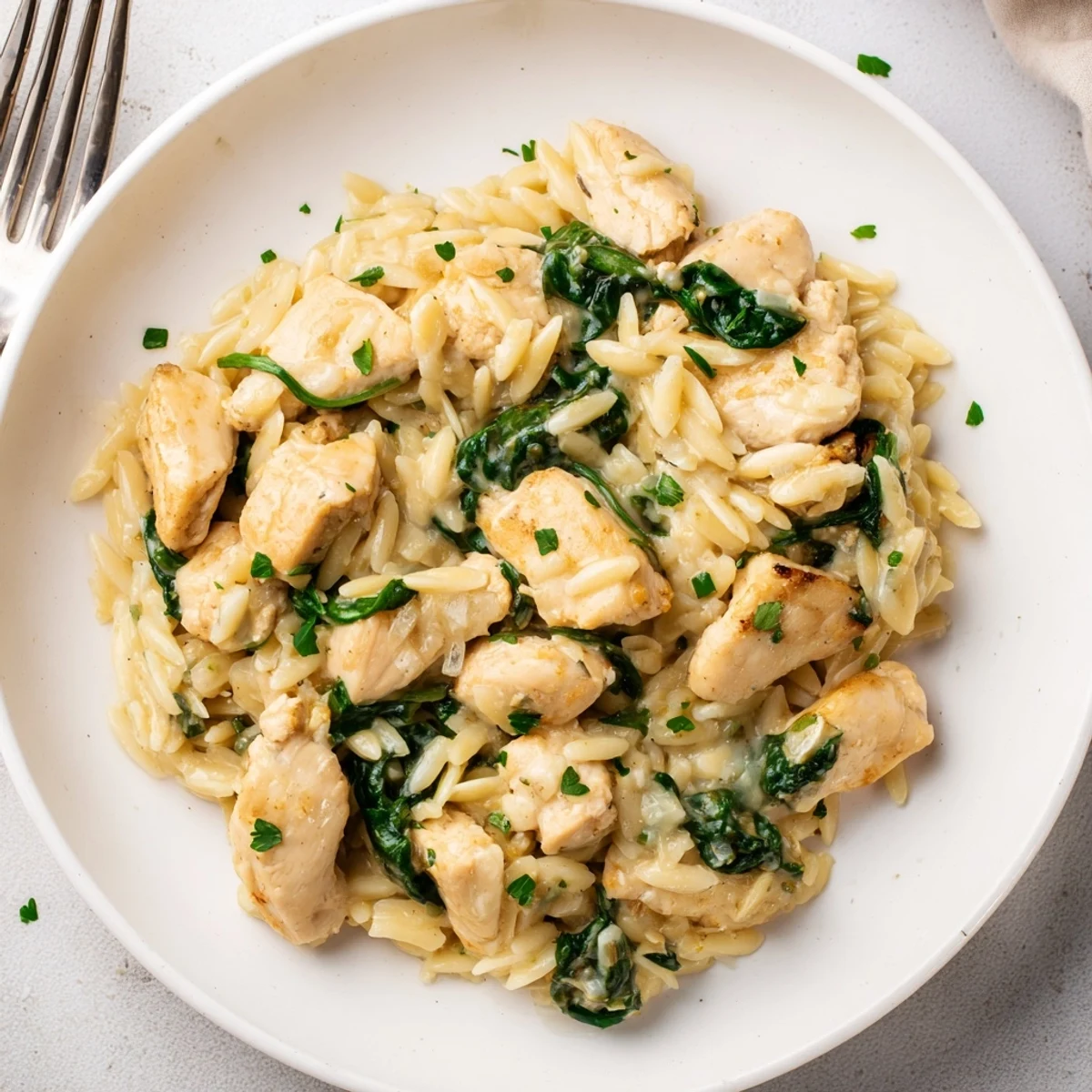Golden chicken pieces simmered with orzo pasta spinach and melted Boursin cheese