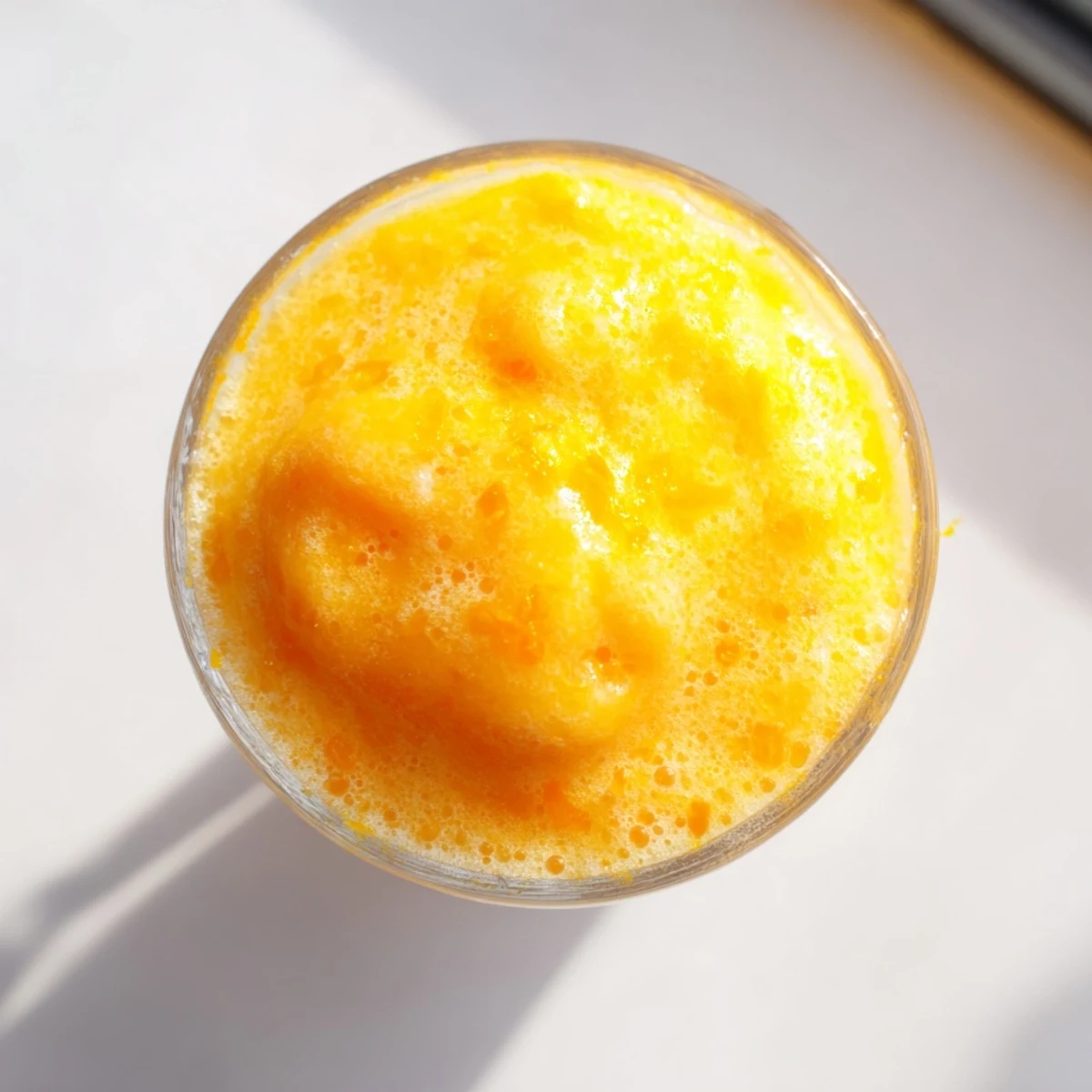 Frosty glass of Sun Kissed Frozen Orange Cream Slush topped with fresh orange wedge garnish