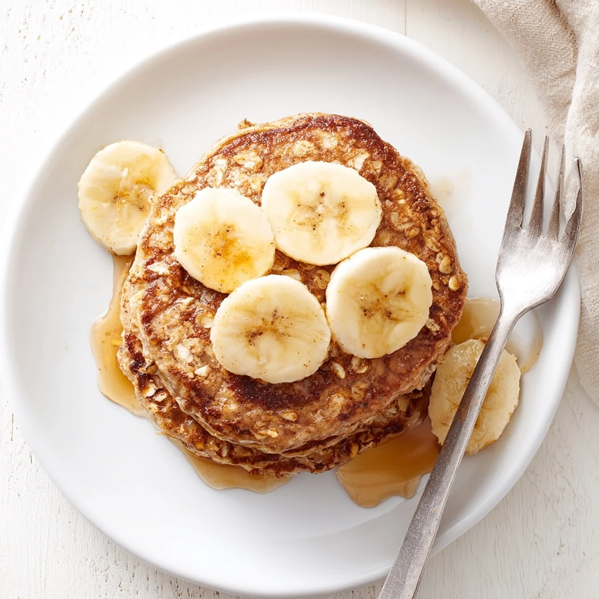 Plate of warm protein banana pancakes dusted with cinnamon and chopped walnuts for texture