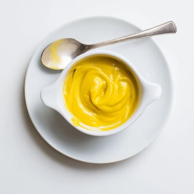 Smooth egg-free mango curd spooned onto toasted bread with fresh mango garnish