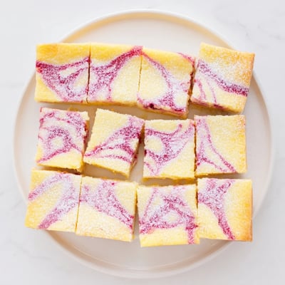 Freshly baked lemon raspberry swirl bars featuring marbled raspberry and lemon layers atop a golden brown shortbread base