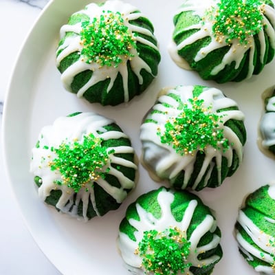 Moist St. Patricks green velvet mini bundt cakes with white glaze on wire rack