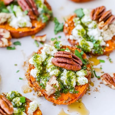 Appetizer spread featuring honey feta sweet potato crostini arranged on serving platter with herb drizzle garnish